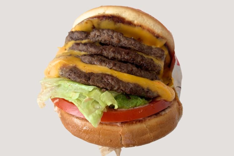 A burger with four patties, cheese, tomatoes and lettuce