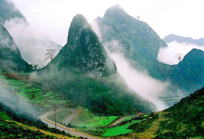 Toàn cảnh làng văn hóa du lịch Lũng Cẩm từ trên cao với lớp sương mù mờ ảo và dãy núi hùng vĩ tạo nên khung cảnh tuyệt đẹp