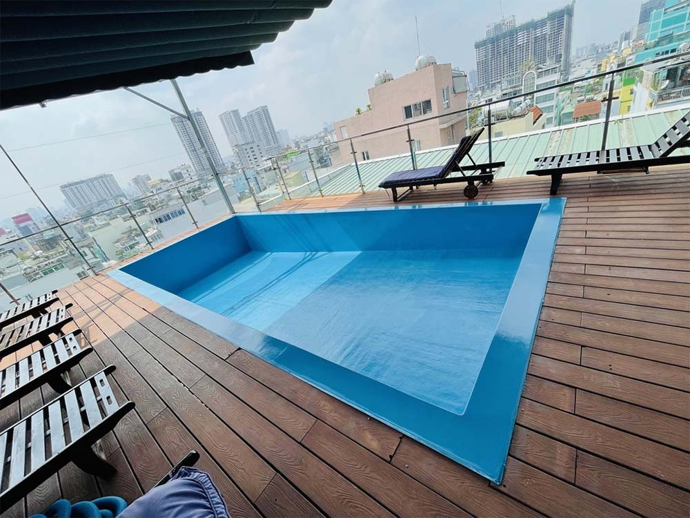 Bể bơi ngoài trời tại A25 Hotel với làn nước trong xanh và ghế dài phơi nắng, tạo không gian thư giãn lý tưởng dưới ánh nắng mặt trời tại khách sạn 3 sao quận 1 A25 Hotel