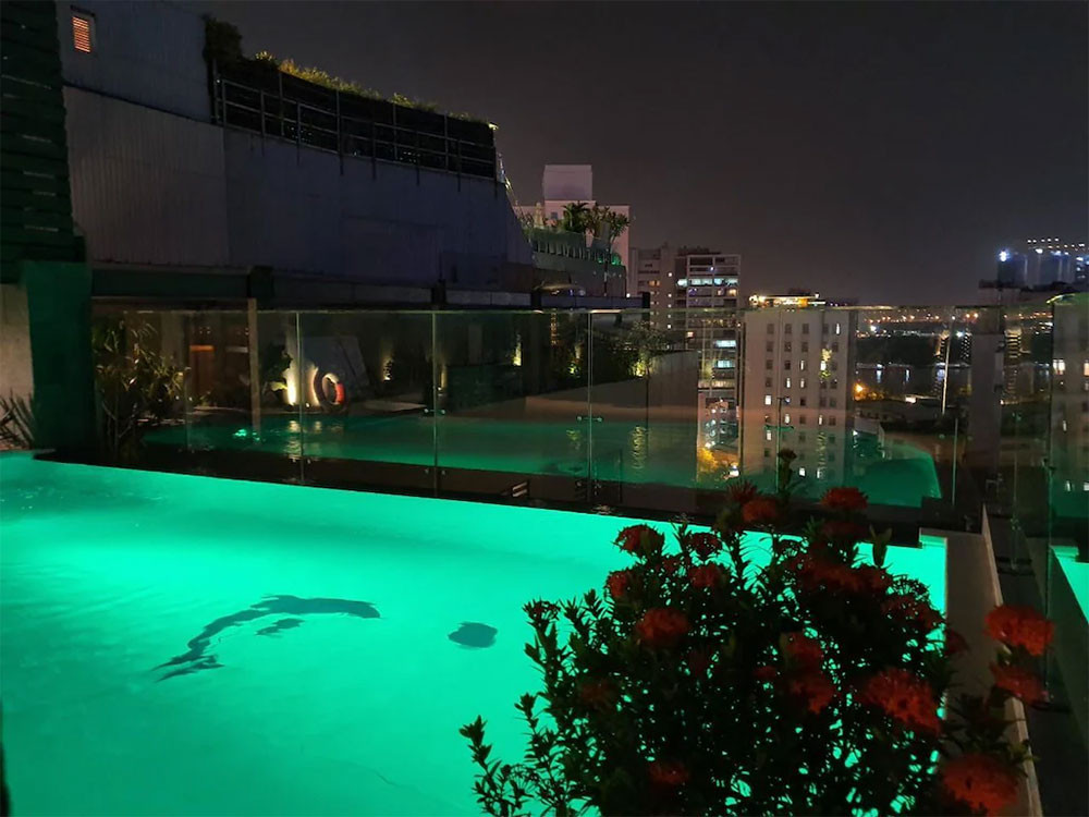 Bể bơi tại SUNFLOWER CBQ HOTEL về đêm, với ánh đèn lấp lánh và tầm nhìn ra thành phố, tạo không gian lãng mạn và thư giãn độc đáo tại khách sạn 3 sao quận 1 SUNFLOWER CBQ HOTEL