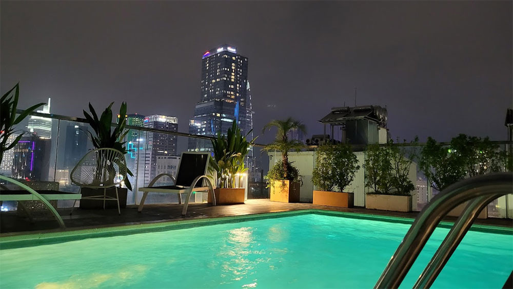 Bể bơi trên tầng thượng của Jovia Hotel vào ban đêm, với ánh đèn lung linh và tầm nhìn ra quang cảnh thành phố, tạo không gian thư giãn tuyệt vời tại khách sạn 3 sao quận 1 Jovia Hotel