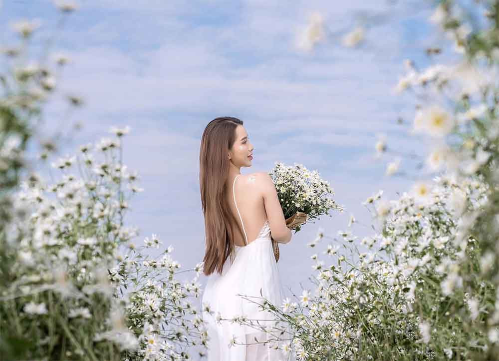 Cô gái tạo dáng nhẹ nhàng giữa cánh đồng cúc họa mi trắng muốt
