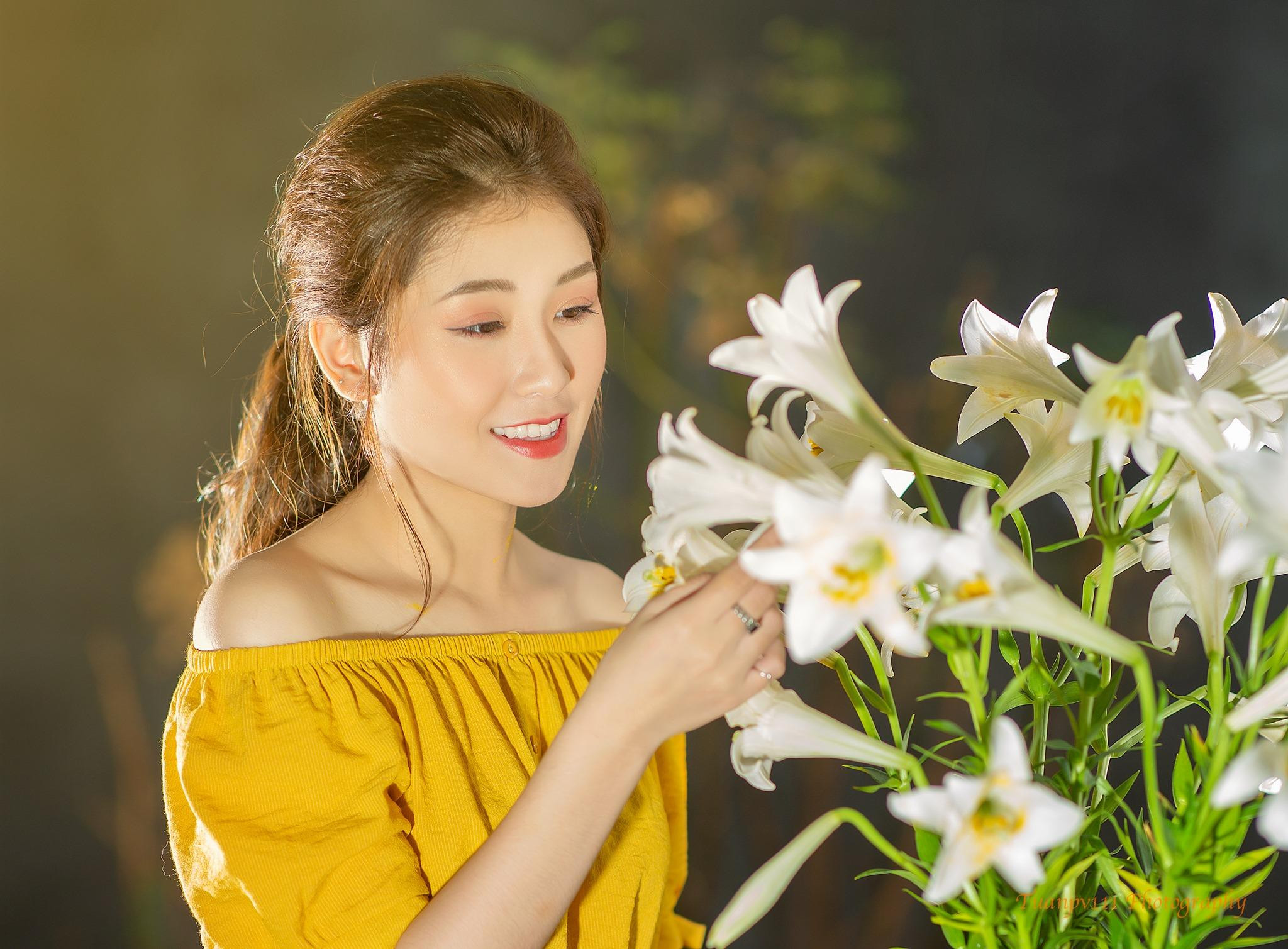 Cô gái tạo dáng với bó hoa loa kèn trắng dịu dàng trong studio