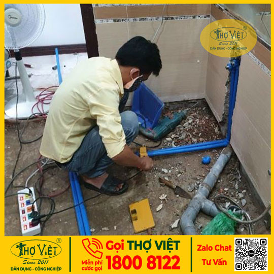 Người thợ đang sửa đường ống nước nóng bằng các dụng cụ chuyên dụng