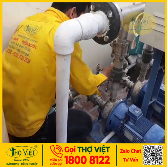 Người thợ đang kiểm tra và sửa chữa máy bơm nước tại một khu dân cư