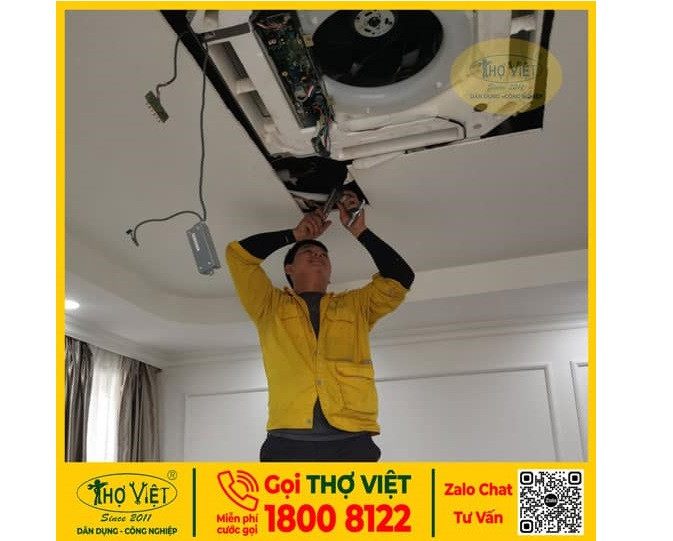 Thợ sửa máy lạnh âm trần đang kiểm tra thiết bị ở văn phòng hoặc cửa hàng