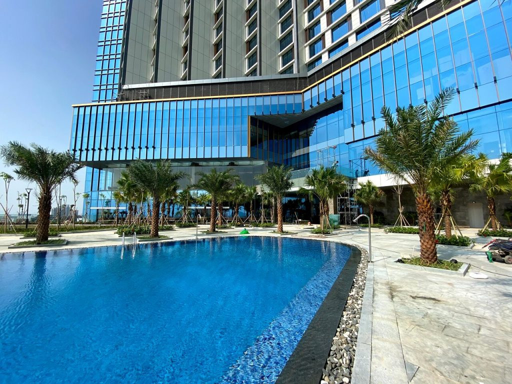 Khu vực bể bơi ngoài trời rộng rãi của Mường Thanh Grand Hotel Hạ Long, với ghế thư giãn và cây xanh xung quanh, là một tiện ích được yêu thích tại khách sạn có bể bơi ở Hạ Long