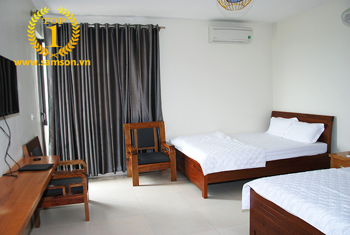 Nội thất phòng nghỉ tiêu chuẩn tại Khách sạn Hải Lý Sầm Sơn, với hai giường đôi thoải mái và khu vực ngồi nhỏ