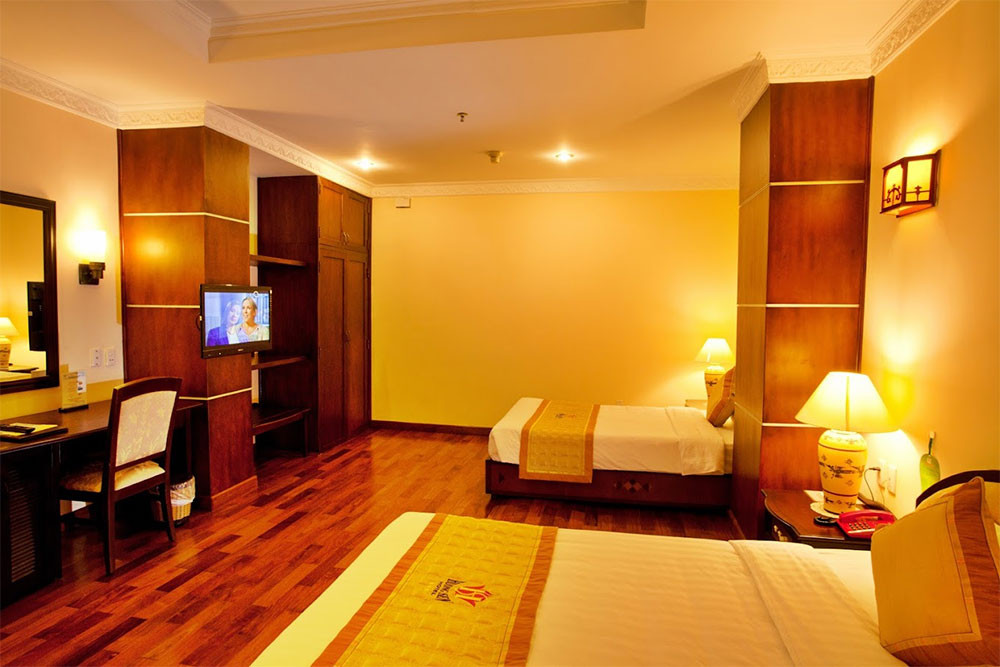 Phòng nghỉ ấm cúng tại Huong Sen Hotel với nội thất gỗ truyền thống, TV màn hình phẳng và cửa sổ lớn, mang lại sự thoải mái cho du khách tại khách sạn 3 sao quận 1 Huong Sen Hotel