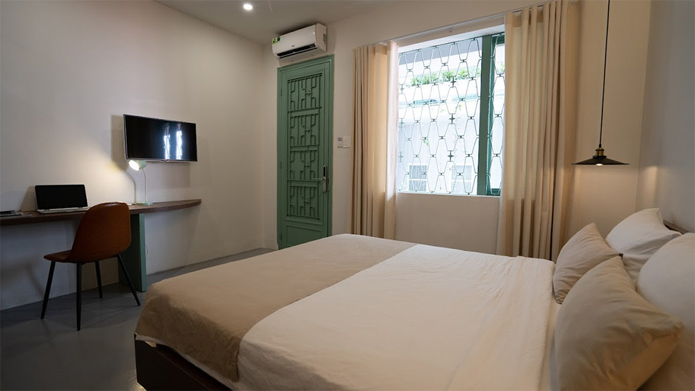 Phòng ngủ ấm cúng tại La Memoria Hotel với giường lớn, nội thất gỗ và ánh sáng dịu nhẹ, mang lại không gian thư thái cho du khách tại khách sạn 3 sao quận 1 La Memoria Hotel