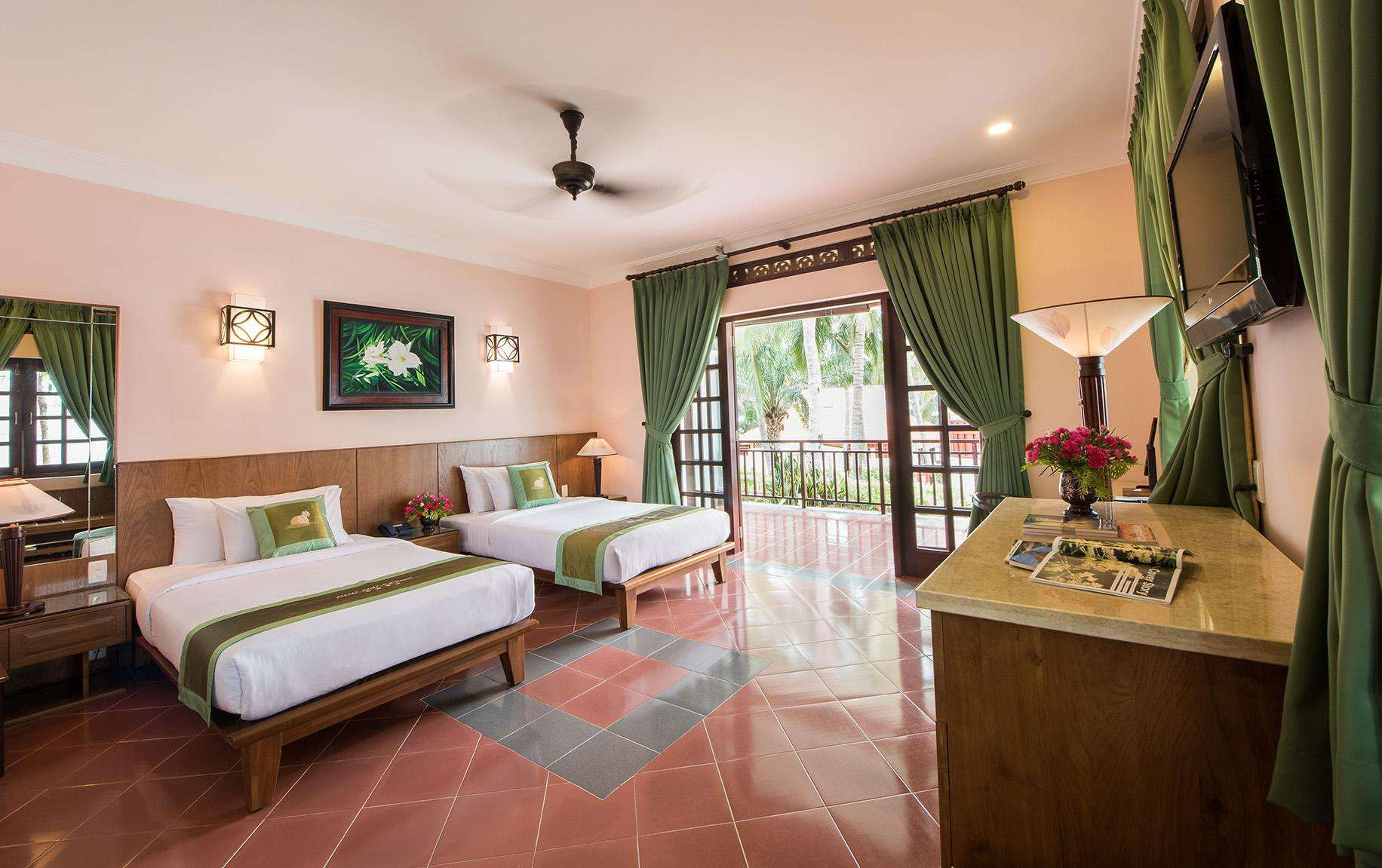 Phòng ngủ mang tông màu ấm áp tại Phu Hai Beach Resort &amp; Spa, một khách sạn gần bãi biển Đồi Dương với nhiều hoạt động thể thao.